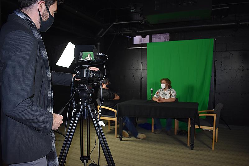 Two students work on a video project in the television studio with faculty member Gyuri Kepes